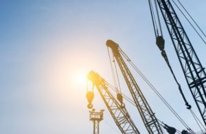 Imagem dos braços de guindastes mostrando apenas os cabos de aço e as polias.