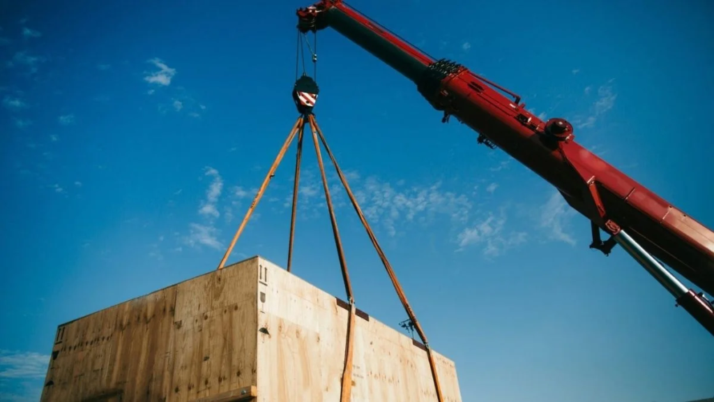 NR 11 transporte, movimentação, armazenagem e manuseio de materiais: guia de compliance para a indústria 2 Guindaste com cintas de elevação movimentando caixa de madeira