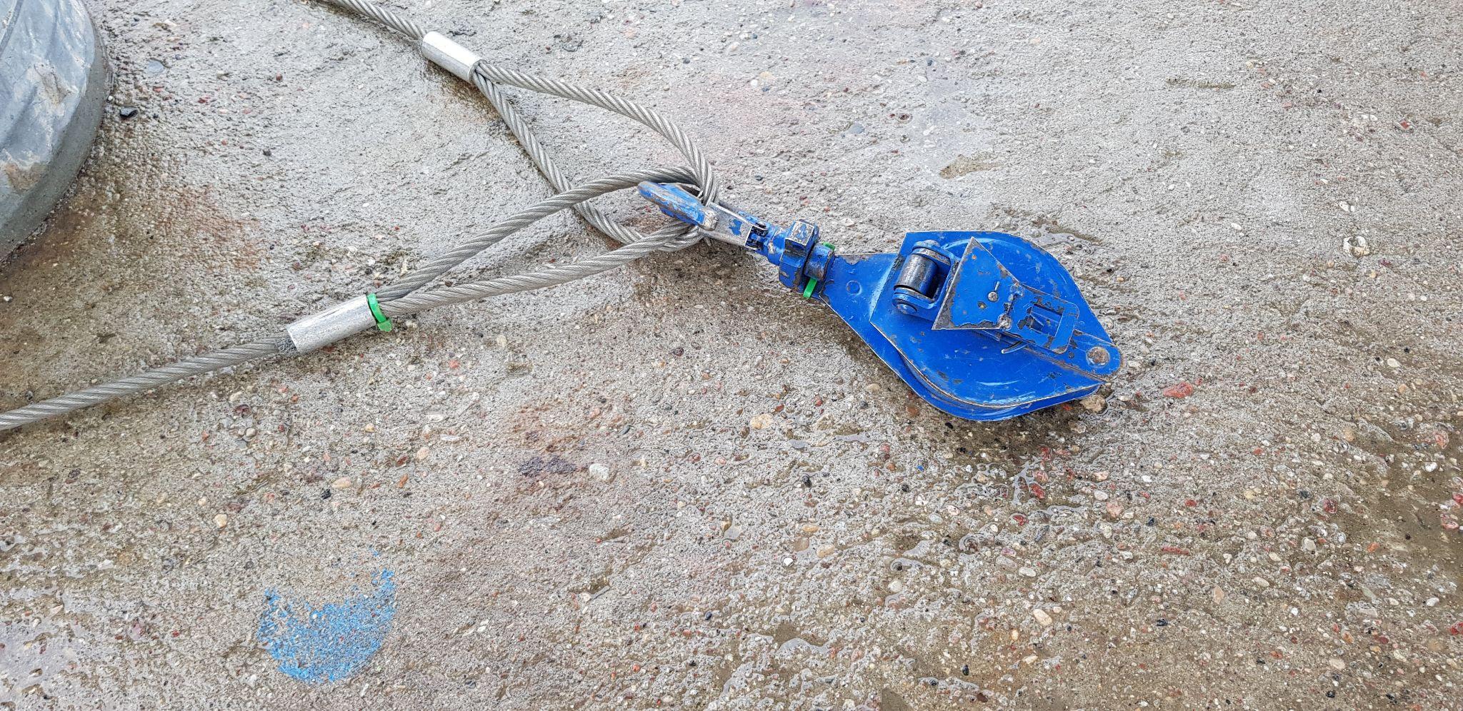 Patesca para guincho com gancho e cabos de aço suspensos em operação ao ar livre.